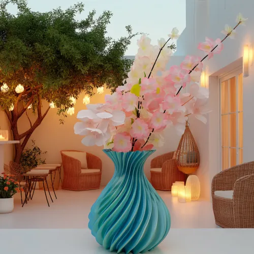 Een turquoise vaas met roze en witte bloemen op een terras, omringd door rotanstoelen en sfeerverlichting.