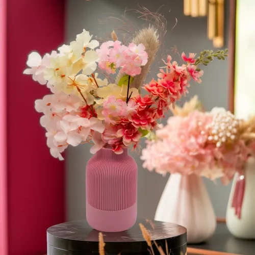 Roze vaas met kleurrijk boeket van witte, roze en rode bloemen.