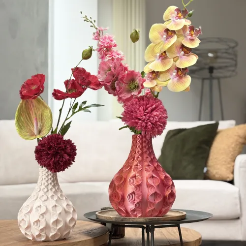 Twee decoratieve vazen met kleurrijke bloemen op houten tafels in een moderne woonkamer met een bank en kussens.