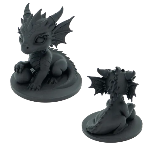 Twee zwarte miniatuurbeeldjes van schattige draken met hoorns en vleugels, een zittend met een bal en de ander van achteren gezien.