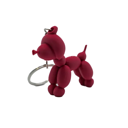 Sleutelhanger in de vorm van een rode ballonhond, gemaakt van matte, ronde vormen.