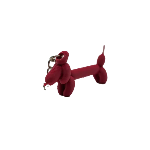 Rode sleutelhanger in de vorm van een ballonhond tegen een witte achtergrond.