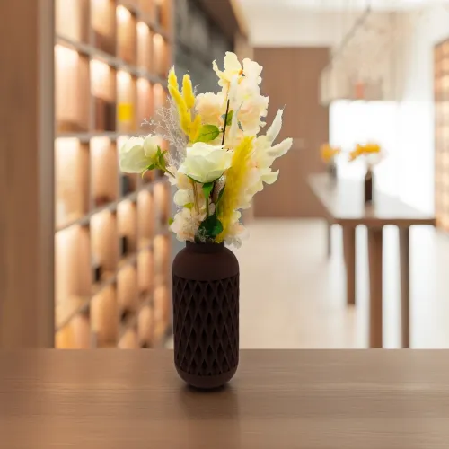 Vaas met decoratieve bloemen en bladeren op een houten tafel, met een moderne interieurachtergrond.
